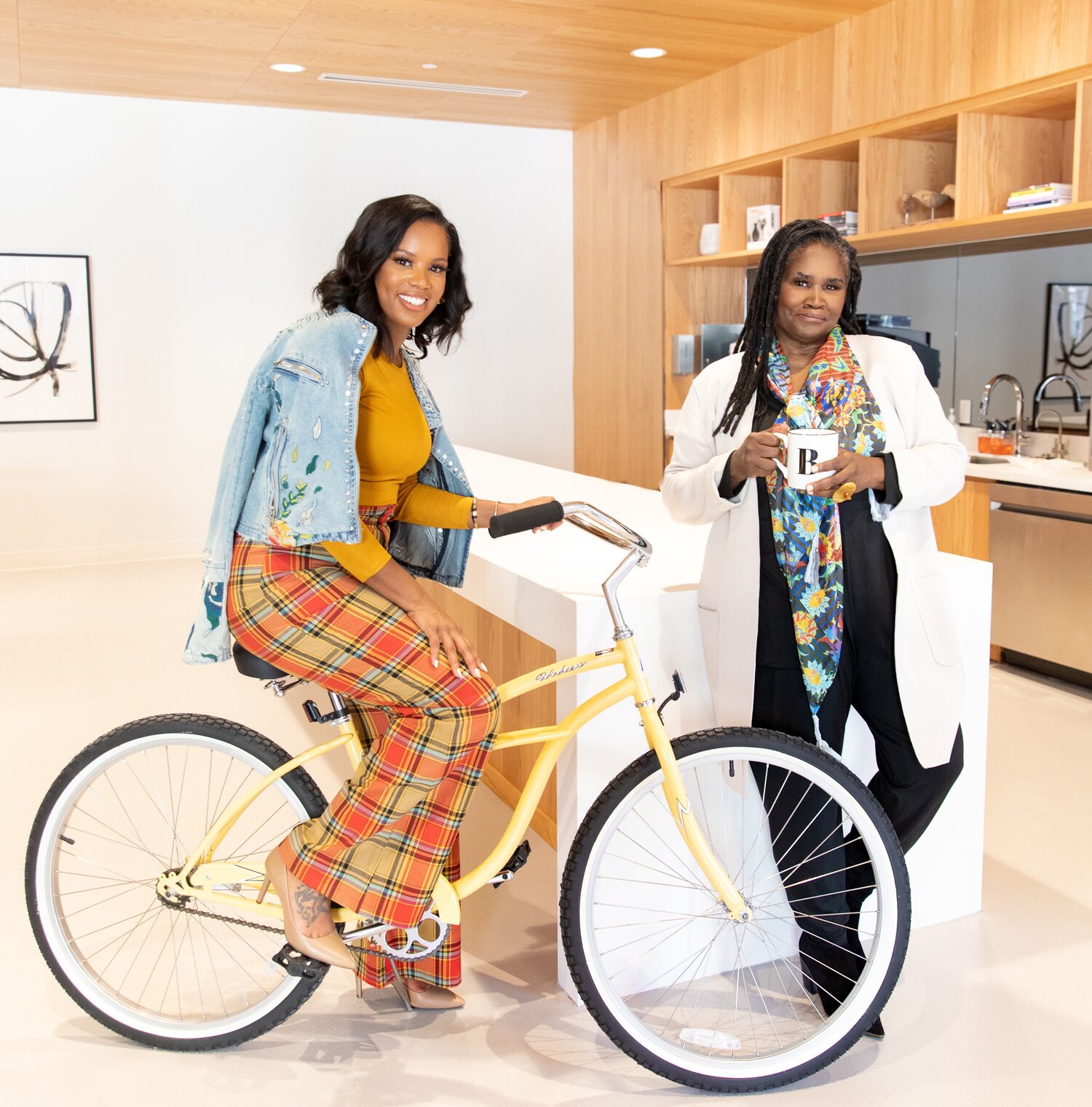 Two women posing beside a yellow bike, radiating joy and friendship.
